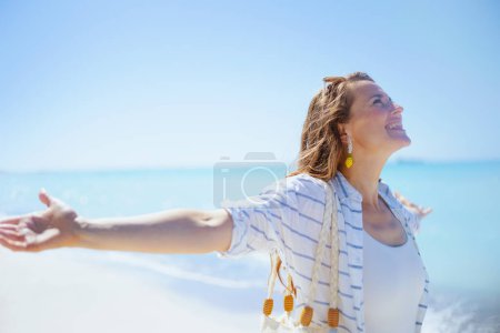 Téléchargez les photos : Smiling stylish 40 years old woman at the beach rejoicing. - en image libre de droit