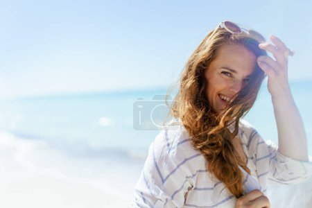 Photo for Portrait of happy modern woman at the beach adjusting hair. - Royalty Free Image
