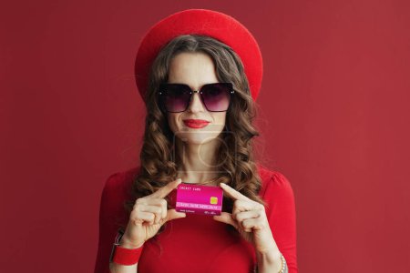 Téléchargez les photos : Happy Valentine. elegant woman with long wavy hair in red dress and beret against red background with credit card. - en image libre de droit