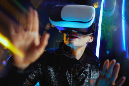 Photo for Modern middle aged woman in metaverse in vr goggles exploring. - Royalty Free Image