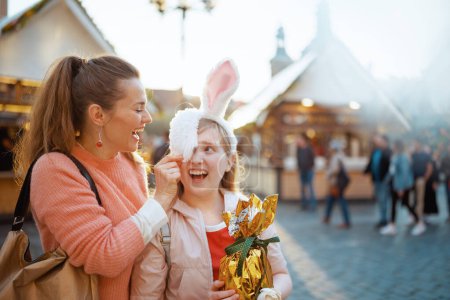 Foto de Easter fun. happy modern mother and child with golden easter egg at the fair in the city. - Imagen libre de derechos