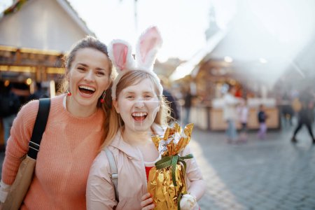 Photo for Easter fun. Portrait of smiling modern mother and child with golden easter egg at the fair in the city. - Royalty Free Image