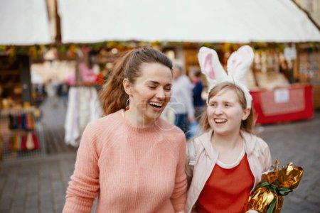 Foto de Easter fun. happy young mother and child with golden easter egg at the fair in the city. - Imagen libre de derechos