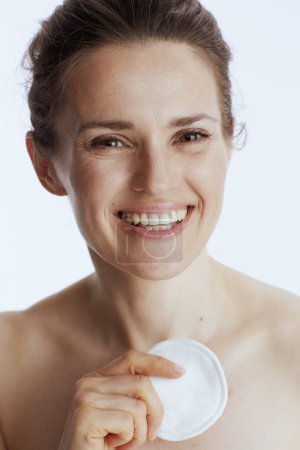 Téléchargez les photos : Smiling middle aged woman with cotton pad against white background. - en image libre de droit