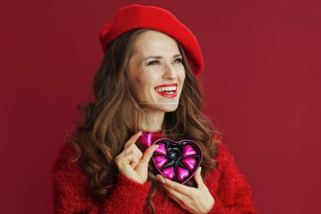 Téléchargez les photos : Happy Valentine. happy elegant middle aged woman in red sweater and beret with heart shaped candy box. - en image libre de droit