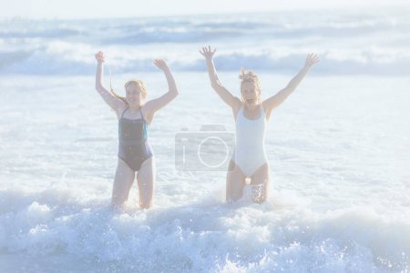 Foto de Smiling modern mother and child at the beach in swimsuit having fun time. - Imagen libre de derechos
