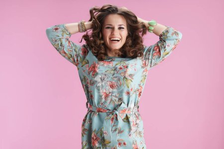 Photo for Happy 40 years old woman with long wavy brunette hair jumping isolated on pink background. - Royalty Free Image