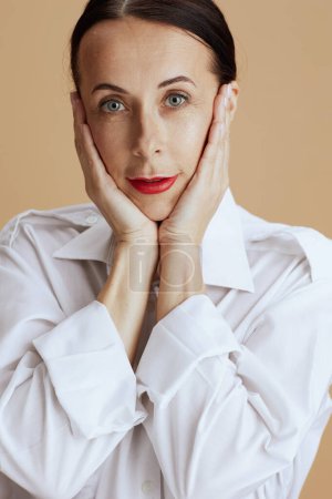 Foto de Modern middle aged woman in white shirt isolated on beige. - Imagen libre de derechos