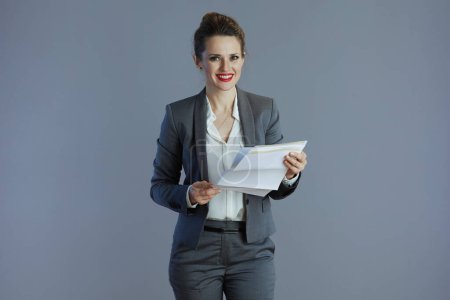 Foto de Feliz 40 años de edad dueño de una pequeña empresa mujer en traje gris con documento aislado en gris. - Imagen libre de derechos