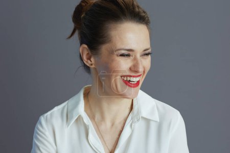 Foto de Happy young female employee in white blouse against grey background. - Imagen libre de derechos