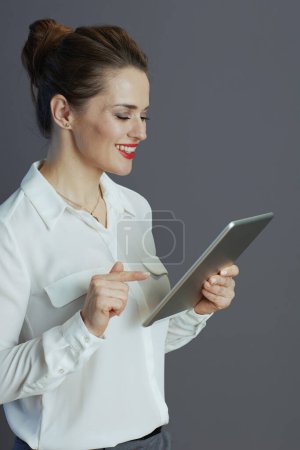 Photo for Happy modern 40 years old business woman in white blouse with tablet PC isolated on grey. - Royalty Free Image
