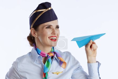 Photo for Happy elegant air hostess woman isolated on white background in uniform with blue paper airplane. - Royalty Free Image