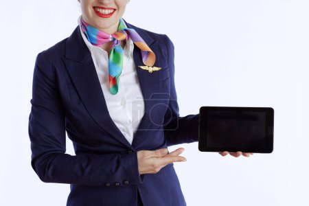 Photo for Closeup on elegant female air hostess isolated on white background in uniform showing tablet PC blank screen. - Royalty Free Image