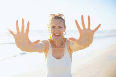 Foto de Smiling stylish 40 years old woman in white swimwear at the beach having fun time. - Imagen libre de derechos