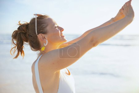Téléchargez les photos : Heureuse femme élégante en blanc beachwear à la plage relaxant. - en image libre de droit