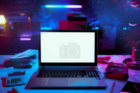 Téléchargez les photos : Neon metaverse futuristic concept. modern office with table, laptop with blank screen and calculator. - en image libre de droit