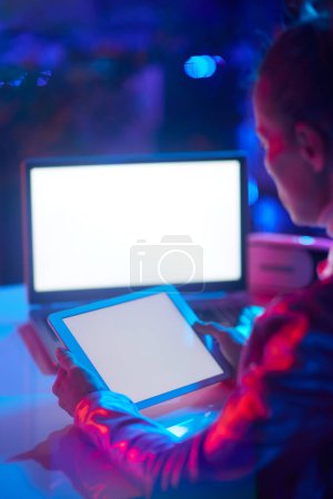 Téléchargez les photos : Vu de derrière femme d'affaires moderne avec écran blanc ordinateur portable et tablette PC écran blanc. - en image libre de droit