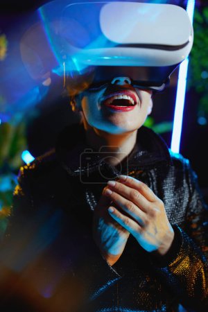 Téléchargez les photos : Smiling stylish middle aged woman in virtual reality in vr goggles. - en image libre de droit