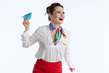 Foto de Sonriente elegante azafata mujer sobre fondo blanco en uniforme con avión de papel azul. - Imagen libre de derechos