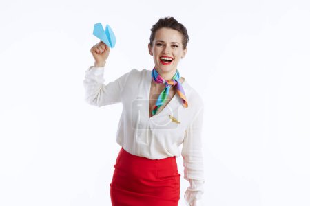 Téléchargez les photos : Heureuse hôtesse élégante femme sur fond blanc en uniforme avec avion en papier bleu. - en image libre de droit