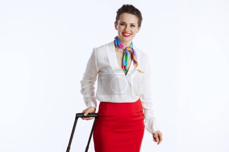 Foto de Happy stylish female air hostess isolated on white background in uniform with trolley bag. - Imagen libre de derechos