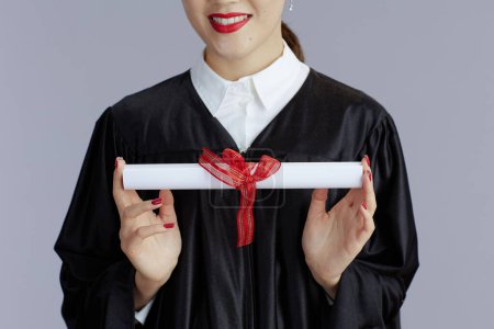 Foto de Closeup on happy young female asian graduate student with diploma isolated on grey background. - Imagen libre de derechos