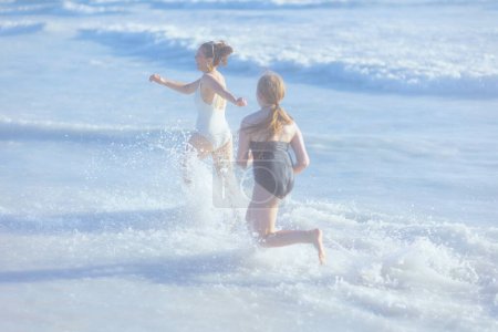 Foto de Feliz madre y el niño con estilo en la playa en ropa de playa corriendo. - Imagen libre de derechos