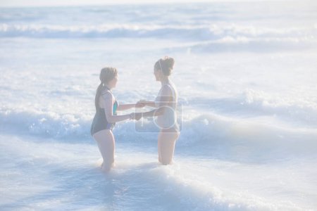 Photo for Modern mother and teenage daughter at the beach in swimwear. - Royalty Free Image