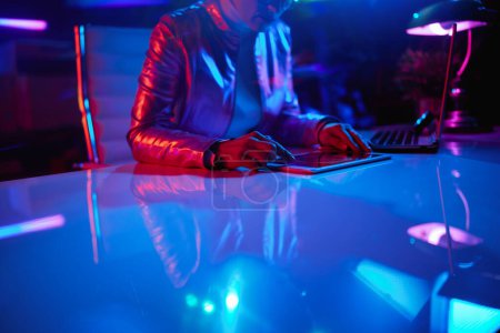 Téléchargez les photos : Neon metaverse concept futuriste. Gros plan sur femme avec tablette PC explorant les graphiques au bureau. - en image libre de droit