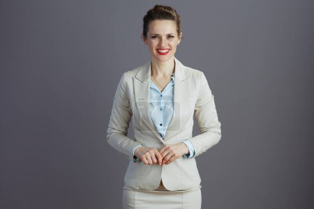 Foto de Sonriente mujer de mediana edad propietaria de una pequeña empresa en un traje de negocios ligero aislado en gris. - Imagen libre de derechos