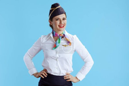 Photo for Happy stylish flight attendant woman against blue background in uniform. - Royalty Free Image
