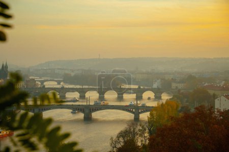 Téléchargez les photos : Paysage avec la rivière Vltava et Karlov le plus au coucher du soleil a filé à travers le feuillage à l'automne à Prague, République tchèque. - en image libre de droit