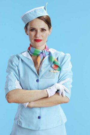 Téléchargez les photos : Élégante hôtesse de l'air féminine sur fond bleu en uniforme bleu. - en image libre de droit