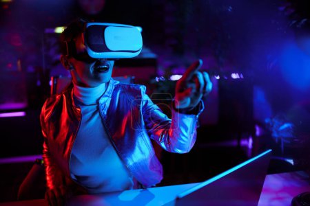 Photo for Neon metaverse futuristic concept. excited modern business woman in vr headset in modern office working in metaverse. - Royalty Free Image