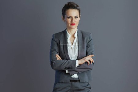 Photo for Modern woman worker in grey suit against gray background. - Royalty Free Image