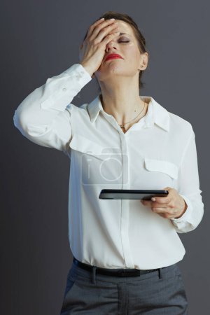 Photo for Stressed trendy woman worker in white blouse with smartphone against grey background. - Royalty Free Image
