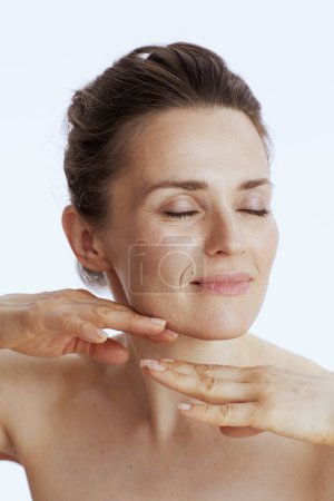 Foto de Moderna hembra haciendo masaje facial contra fondo blanco. - Imagen libre de derechos