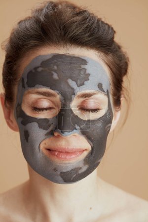 Foto de Mujer moderna de mediana edad relajada con máscara cosmética aislada sobre fondo beige. - Imagen libre de derechos