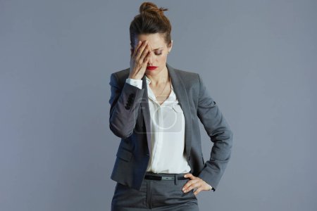 Foto de Estresado elegante 40 años de edad, empleada en traje gris aislado sobre fondo gris. - Imagen libre de derechos