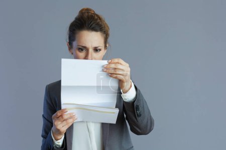 Téléchargez les photos : Élégante femme d'affaires en costume gris avec document isolé sur fond gris. - en image libre de droit
