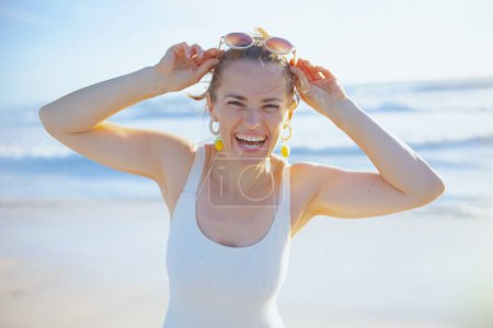Photo for Portrait of smiling elegant 40 years old woman in white swimwear at the beach having fun time. - Royalty Free Image