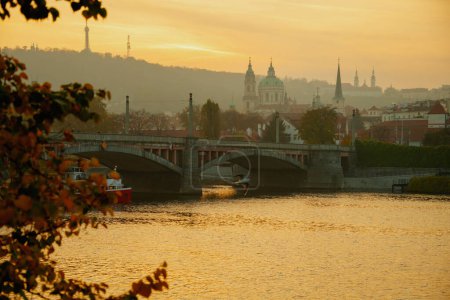 Téléchargez les photos : Paysage avec la rivière Vltava au coucher du soleil filmé à travers le feuillage en automne à Prague, République tchèque. - en image libre de droit