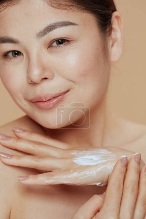 Téléchargez les photos : Femme moderne avec crème pour les mains sur fond beige. - en image libre de droit