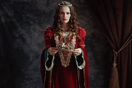 reina medieval en vestido rojo con corona sobre fondo gris oscuro.
