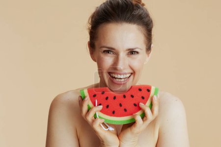 Photo for Smiling modern female with watermelon shower sponge on beige background. - Royalty Free Image