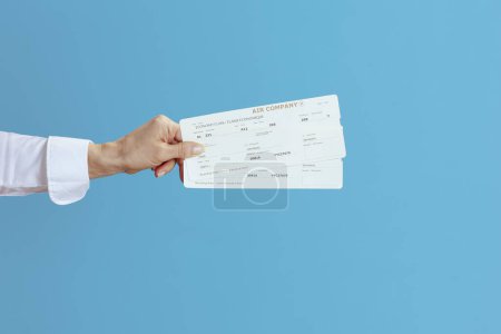 Photo for Closeup on elegant air hostess woman on blue background with flight tickets. - Royalty Free Image