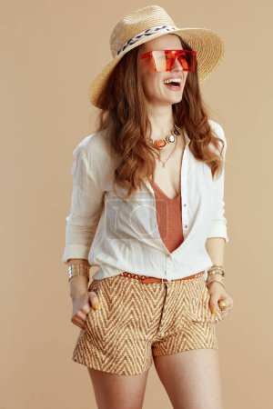 Foto de Vacaciones en playa. mujer de moda feliz en blusa blanca y pantalones cortos aislados en beige con sombrero de paja y gafas de sol. - Imagen libre de derechos