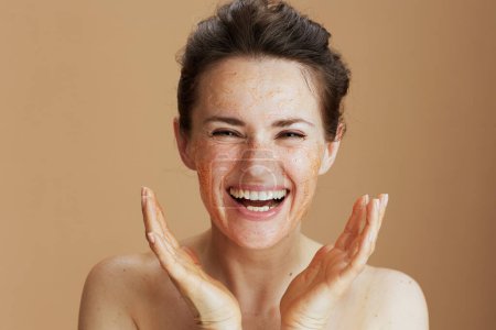 Photo for Smiling modern woman with face scrub against beige background. - Royalty Free Image