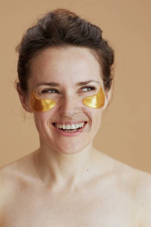 Foto de Hembra moderna feliz con parches oculares aislados sobre fondo beige. - Imagen libre de derechos