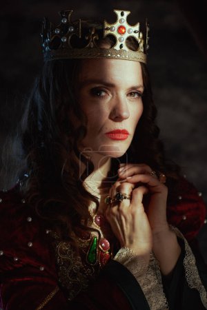 Foto de Reina medieval en vestido rojo con corona sobre fondo gris oscuro. - Imagen libre de derechos